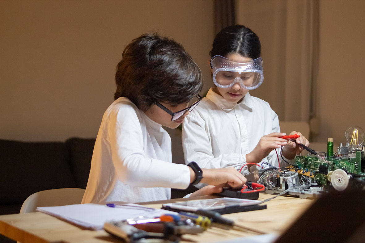 Focused children doing experiment in physics together in school lab. Girl and boy taking measurements. Education, hobby, school concept